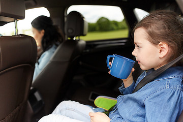 Image showing little girl driving in car and drinking from cup