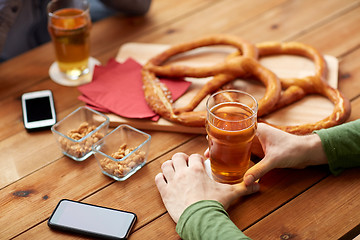 Image showing close up of hands with smartphones and beer at bar