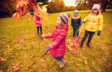 Image showing happy children playing with autumn leaves in park