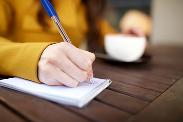 Image showing close up of hand writing to notebook at cafe