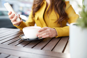 Image showing close up of woman texting on smartphone at cafe