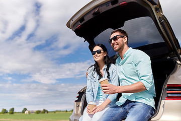 Image showing happy couple with coffee at hatchback car trunk