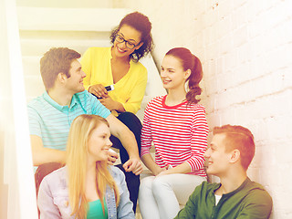 Image showing smiling students with smartphone having discussion