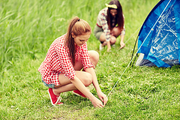 Image showing smiling friends setting up tent outdoors