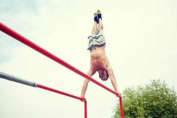 Image showing young man exercising on parallel bars outdoors