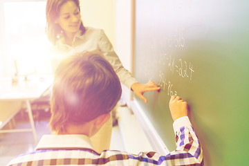 Image showing school boy with teacher writing on chalk board