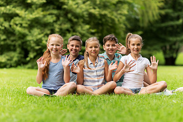 Image showing group of happy kids waving hands outdoors