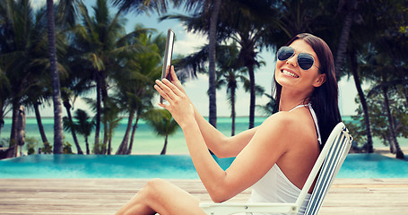 Image showing smiling woman with tablet pc sunbathing on beach