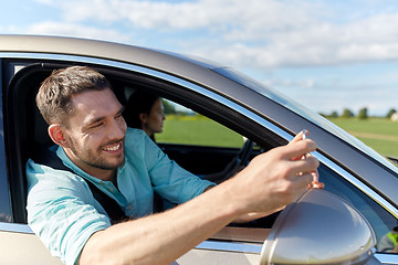 Image showing happy smiling man with smartphone driving in car