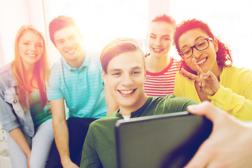 Image showing smiling students making picture with tablet pc