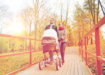 Image showing smiling couple with baby pram in autumn park