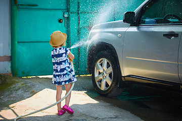 Image showing Little girl helps her parents to wash the car