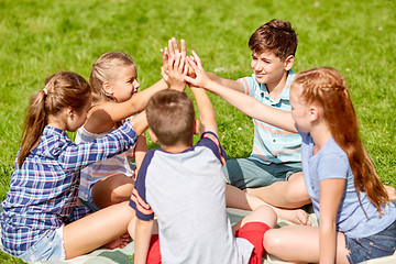 Image showing group of happy kids making high five outdoors