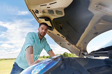 Image showing man with open hood of broken car at countryside