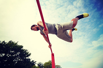 Image showing young man exercising on horizontal bar outdoors