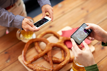 Image showing close up of hands picturing pretzel by smartphone