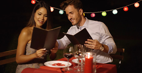 Image showing Loving young couple choosing food off a menu