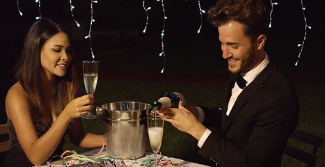 Image showing Man fills his glass with champagne to toast