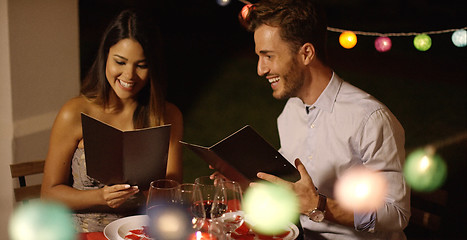 Image showing Young couple laughing as they go through the menu