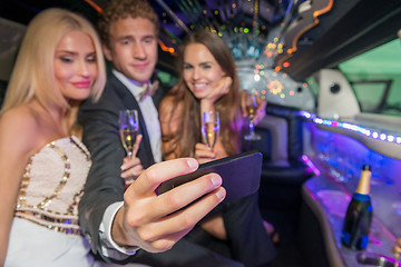 Image showing Young man with female friends taking selfie on mobile phone in l