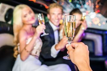Image showing Closeup of hand toasting champagne flute with friends in limousi