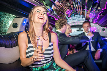 Image showing Cheerful young woman holding champagne flute while friends celeb