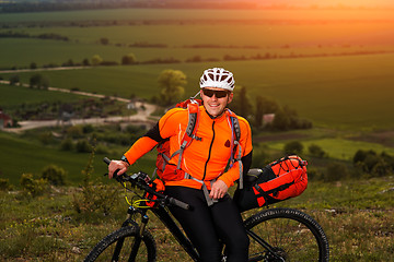 Image showing Young man cycling on a rural road through green meadow