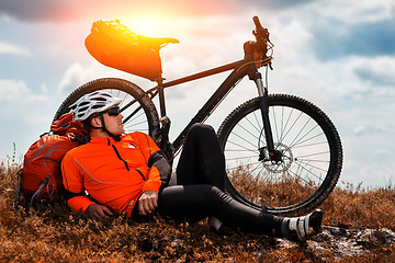 Image showing Young man cycling on a rural road through green meadow