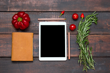 Image showing The tablet, notebook, fresh bitter and sweet pepper on wooden table background