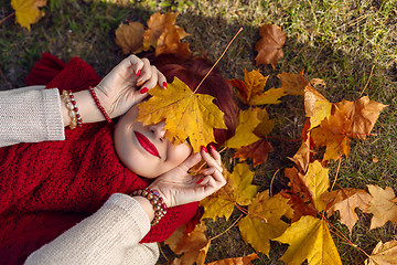 Image showing Red hair girl lying with autumn maple leaf