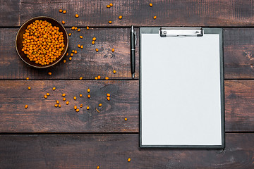 Image showing Office desk table with notebooks, fresh buckthorn berries on wooden table