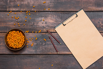 Image showing Office desk table with notebook, fresh buckthorn berries on wooden table