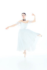 Image showing Ballerina in white dress posing on pointe shoes, studio background.