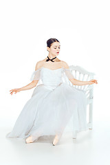 Image showing Ballerina in white dress sitting, studio background.