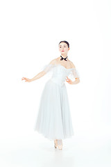 Image showing Ballerina in white dress posing on pointe shoes, studio background.