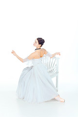 Image showing Ballerina in white dress sitting, studio background.