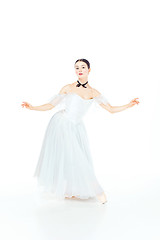 Image showing Ballerina in white dress posing on pointe shoes, studio background.