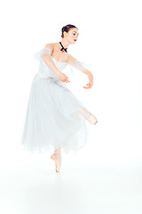 Image showing Ballerina in white dress posing on pointe shoes, studio background.