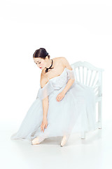 Image showing Ballerina in white dress sitting, studio background.