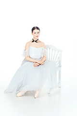 Image showing Ballerina in white dress sitting, studio background.