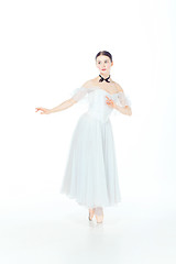 Image showing Ballerina in white dress posing on pointe shoes, studio background.