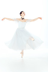 Image showing Ballerina in white dress posing on pointe shoes, studio background.