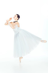 Image showing Ballerina in white dress posing on pointe shoes, studio background.