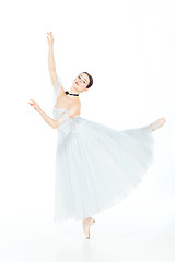 Image showing Ballerina in white dress posing on pointe shoes, studio background.