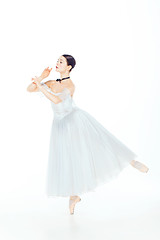 Image showing Ballerina in white dress posing on pointe shoes, studio background.