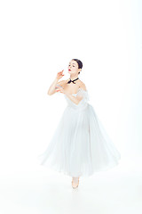 Image showing Ballerina in white dress posing on pointe shoes, studio background.