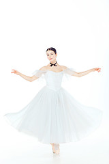 Image showing Ballerina in white dress posing on pointe shoes, studio background.