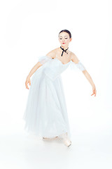 Image showing Ballerina in white dress posing on pointe shoes, studio background.