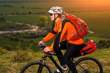 Image showing Young man cycling on a rural road through green meadow