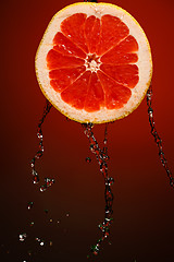 Image showing Fresh water drops on grapefruit at red background